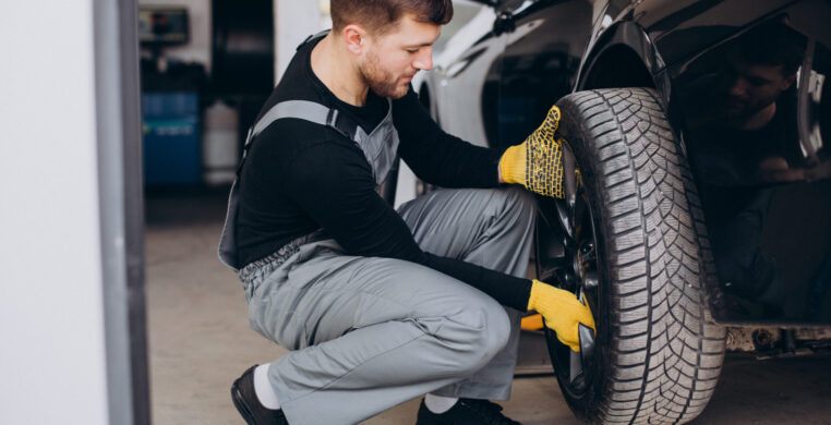 Car mechanic changing wheels in car